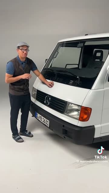 Presenter beside a historic white Mercedes-Benz van.